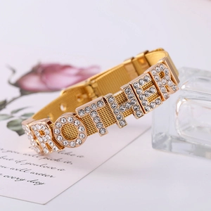 Gold mesh bracelet with crystal MOTHER lettering and adjustable clasp on elegant backdrop