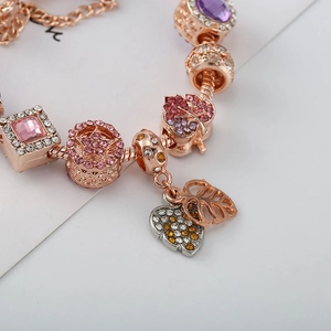 Détail macro du bracelet à charms or rose avec pendentif cœur et perles en cristal