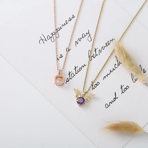 Detail of rose gold square and purple zircon elk necklaces on a white decorative card