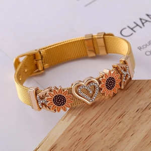 Detail eines goldenen Mesh-Armbands mit Sonnenblumen-Anhängern und Kristallherz-Schnalle