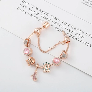 Détail du bracelet charms or rose avec couronne en cristal rose et pendentif cœur