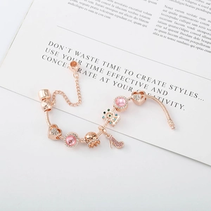 Vue détaillée du bracelet à breloques en or rose avec cœur rose, couronne et chaîne de sécurité