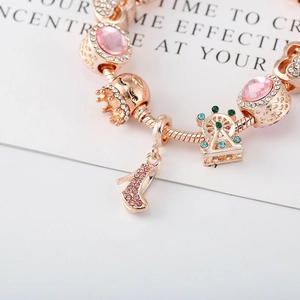 Détails macro du bracelet en or rose avec pierres roses et pendentifs de couronne