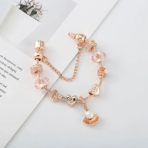 Détail du bracelet à breloques or rose avec cristaux roses, coquillages et perles