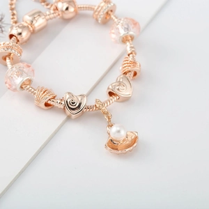 Détail du bracelet à breloques or rose avec perles roses et pendentif perle coquillage