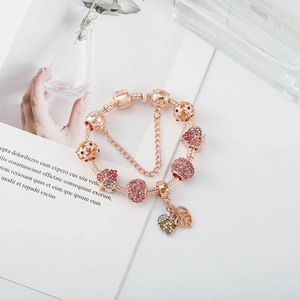 Détail du bracelet à breloques en or rose avec cristaux roses et pendentifs érable