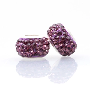 Macro detail of two purple clay beads with four rows of sparkling crystals and silver core