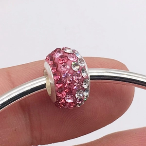 Detailed close-up of pink and clear rhinestone pavé charms on a silver bracelet