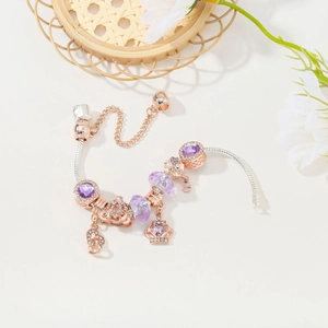 Rose gold charm bracelet with purple crystal beads, crown and carriage pendants