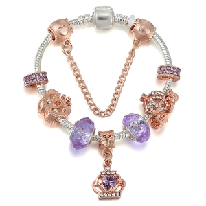 Detail of silver snake chain bracelet with purple charms, crown pendant and safety chain