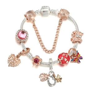 Macro detail of silver snake chain bracelet with rose gold charms and floral pendants