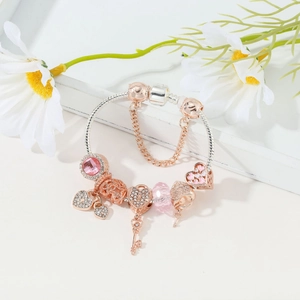 Detailed macro view of silver snake chain bracelet with rose gold charms and pink crystal