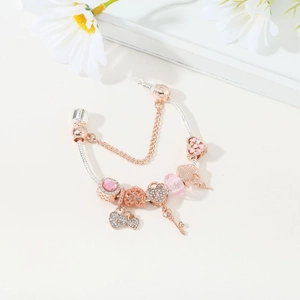 Detail of rose gold snake chain bracelet with pink crystal charms and key pendant