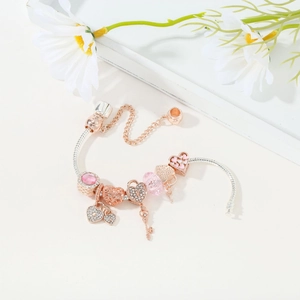 Detail of silver snake chain bracelet with rose gold charms and pink crystals