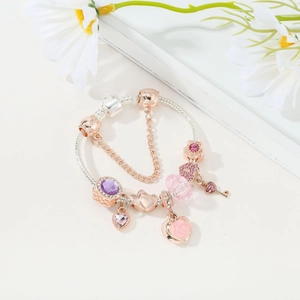 Detail of rose gold and silver charm bracelet with pink crystal hearts and key pendant