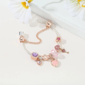 Detail of rose gold snake chain bracelet with purple charms and heart pendants