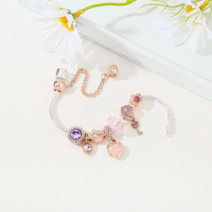 Detailed macro view of silver snake chain bracelet with rose gold charms and purple stones