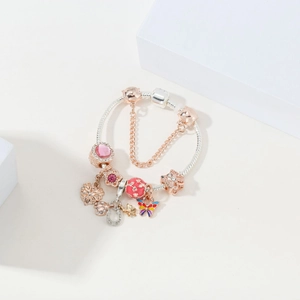 Detail of silver snake chain bracelet with rose gold charms and pink crystal heart