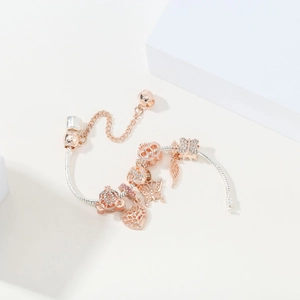 Detailed close-up of two-tone snake chain bracelet with rose gold pumpkin and heart charms