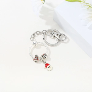 Detailed view of silver Christmas keychain with Santa charm and enamel hat on white stand