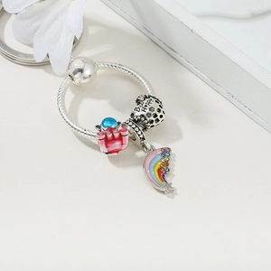 Detailed shot of a silver keychain with pink castle, Bee Happy bead, and rainbow charms