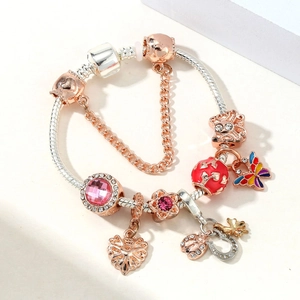 Detail of rose gold charm bracelet with pink crystal, butterfly pendant and snake chain