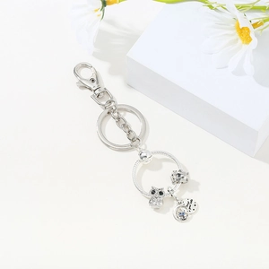 Macro detail of silver owl charm with Love Your Life tag on a stylish keychain
