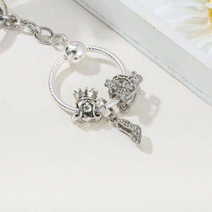 Macro detail of silver charm pendant featuring a crown girl, pumpkin coach, and high heel