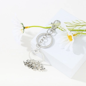 Detailed view of silver metal keychain with cute 3D cartoon animal charms on a white block