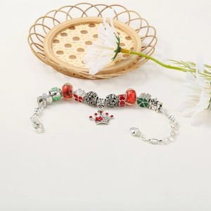 Macro detail of Christmas charm bracelet with red rhinestone crown and enamel heart beads