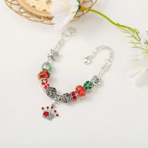 Detail of a silver charm bracelet with red rhinestone crown and green enamel beads