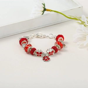 Detailed macro view of red faceted glass beads and crystal flower charms on a silver chain