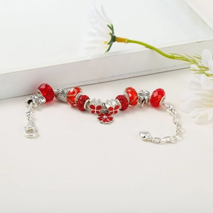 Macro detail of Christmas charm bracelet with red crystal beads and floral pendant
