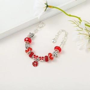 Close-up of silver charm bracelet with red crystal beads and enamel flower pendant