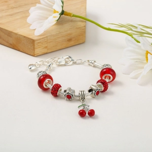Detail of red beaded bracelet featuring a cherry charm and silver floral accents
