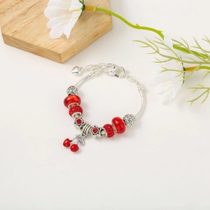 Detail of a Pandora-style charm bracelet with red crystal beads and cherry pendant