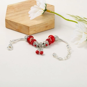 Detail of silver snake chain bracelet with red cherry charm and crystal beads
