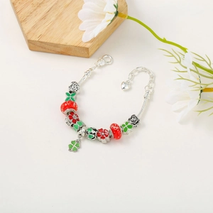 Detailed shot of Christmas charm bracelet with red glass beads and clover pendants