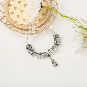 Macro shot of silver snake chain bracelet featuring lucky cat and fortune charms