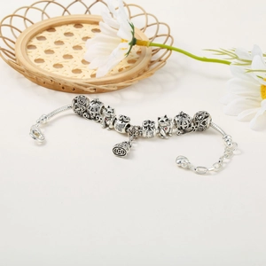 Detail of silver charm bracelet featuring Maneki Neko cat and fortune bag charms