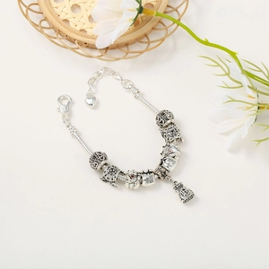 Detailed macro view of silver snake chain bracelet with Fu bag and turtle charms