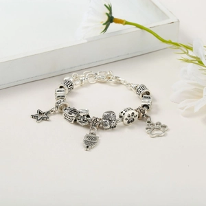 Detail of silver snake chain bracelet with owl, star, and hollow paw print charms