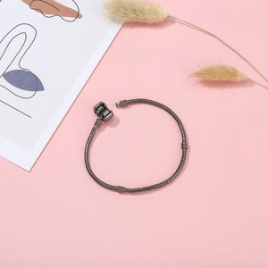 Minimalist gunmetal snake chain bracelet with secure round clasp on pink background