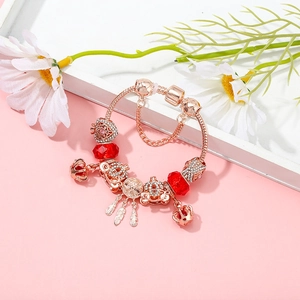 Bracelet maille serpent en or rose avec perles rouges à facettes et breloques de cœur