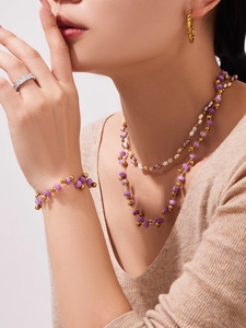 Detail of layered purple crystal bead necklace and gold bracelet set worn by model