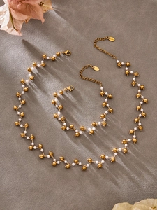 Detail of handmade stainless steel necklace set with golden beads and white pearls