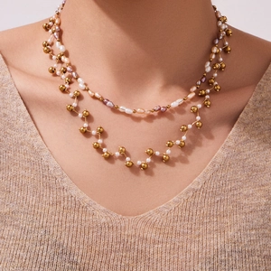 Layered gold necklace with natural crystals and pearls on a model wearing knitwear
