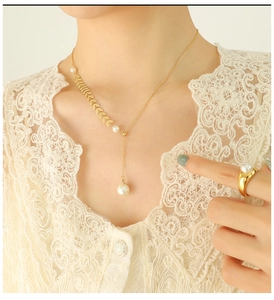 Detail of elegant gold necklace and pearl ring on model with lace background