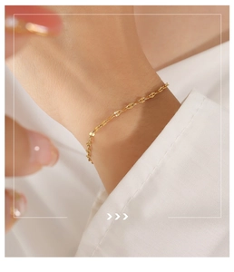 Nahaufnahme eines vergoldeten Titanstahl-Armbands mit einer zarten wellenförmigen Kette