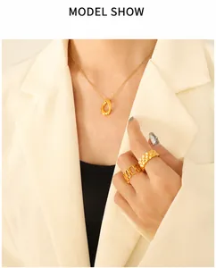 Primo piano di collana e anelli geometrici dorati indossati da una modella in luce soffusa